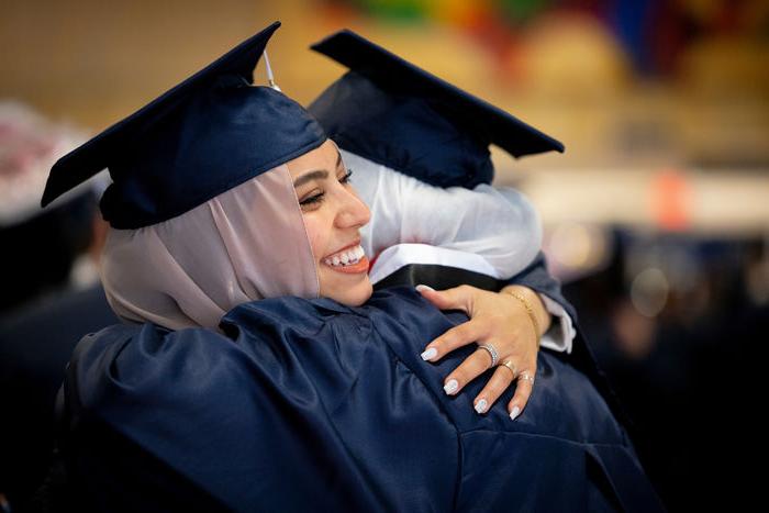 two students hugging in their caps and gowns